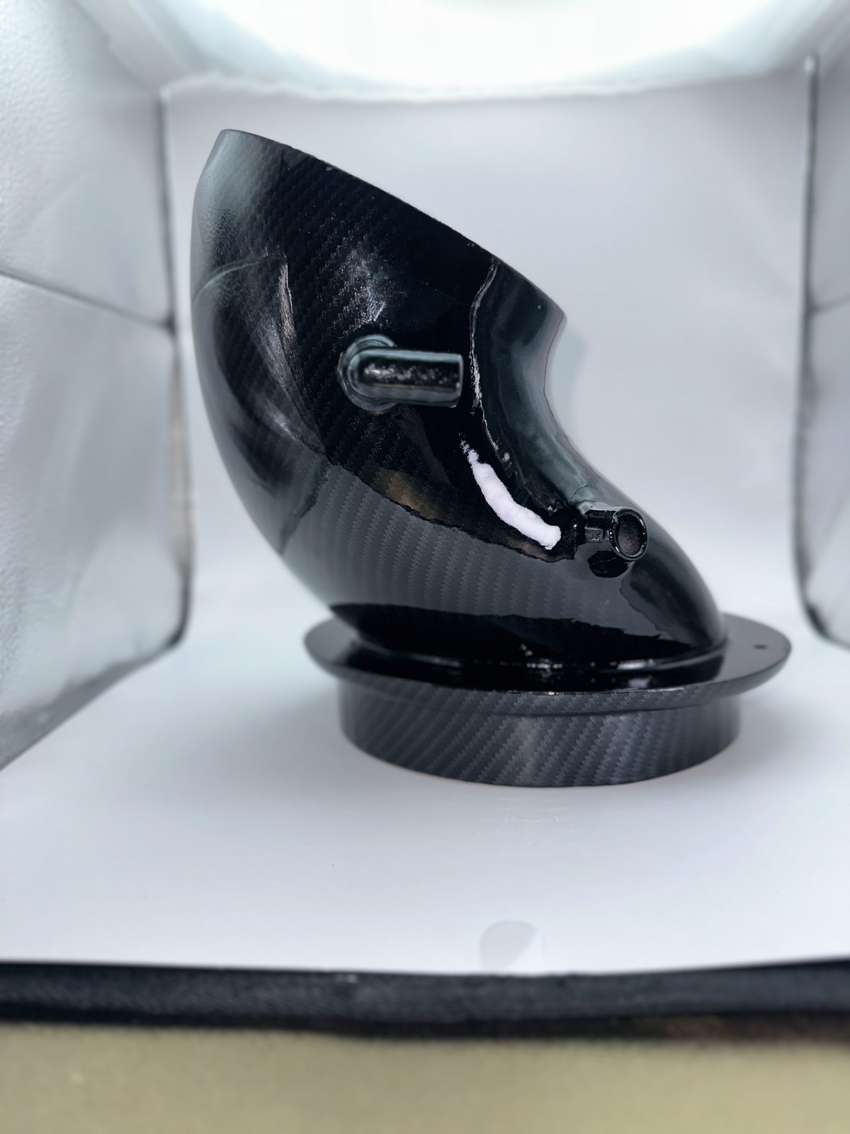 Gloss black intake elbow photographed on a white backdrop